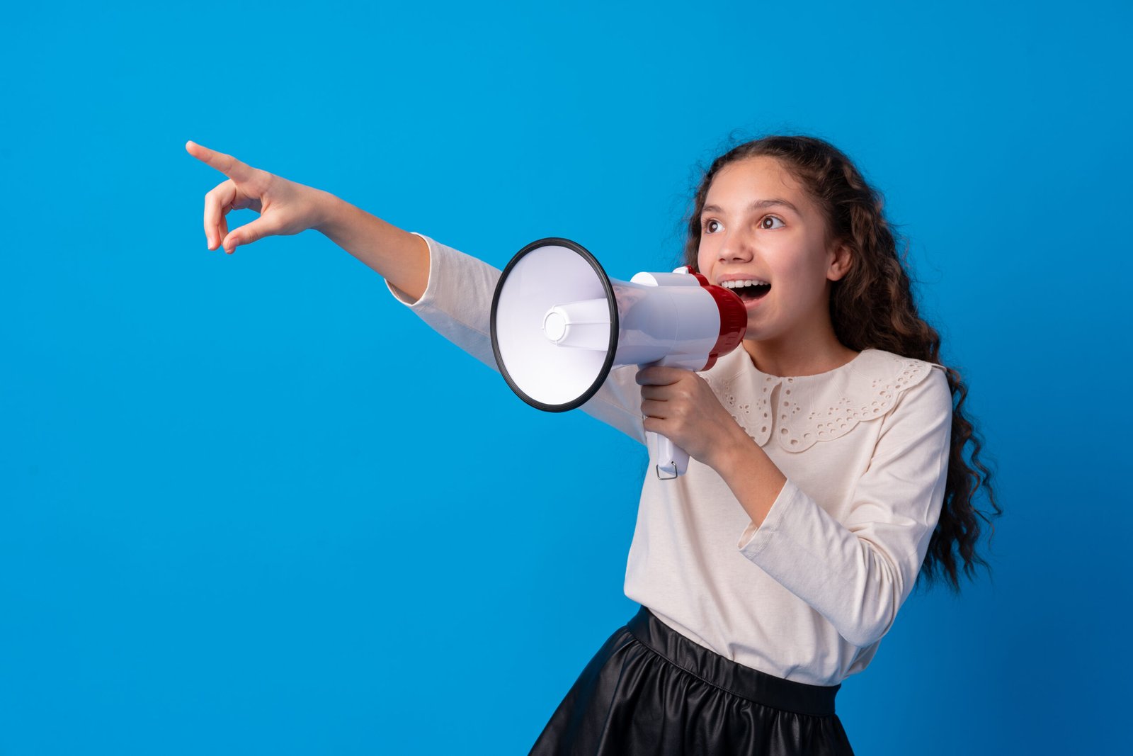 Cute schoolgirl holding megaphone against blue background